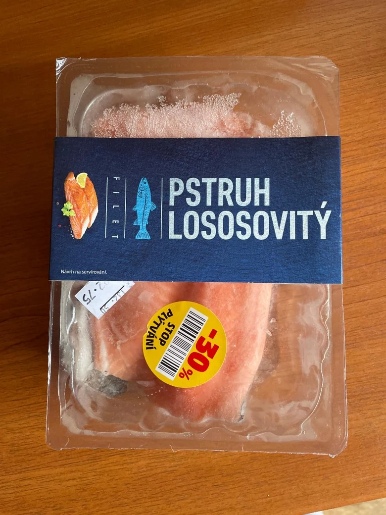 Balancovaný pstruh lososovitý v plastovém obalu na dřevě.