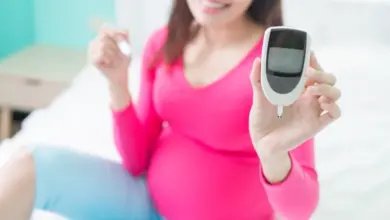Těhotná žena drží glukometr pro měření cukru v krvi.