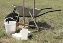 Kolo s kbelíkem a cihly pro stavbu venkovního ohniště.