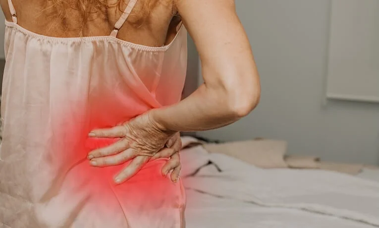 Žena drží dolní část zad kvůli bolesti skříplého nervu.