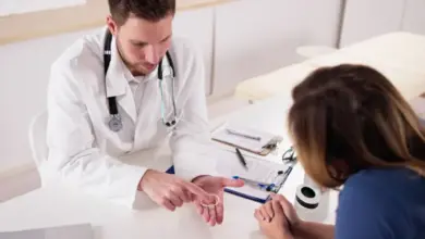 Lékař ukazuje pacientce hormonální vaginální kroužek při vyšetření.