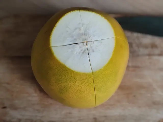 Celý žlutý pomelo rozříznutý na polovinu s bílou dužinou.