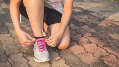 Žena se připoutává na běžecké boty před cvičením venku.