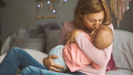 Matka drží své dítě na lůžku v intimitě.