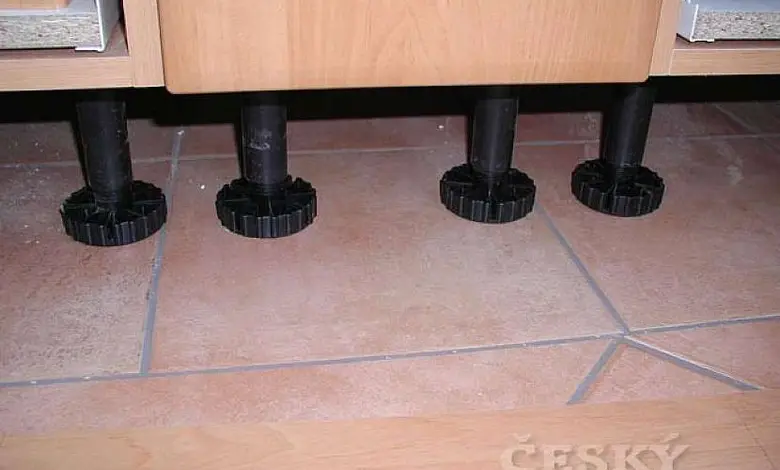 Černé nastavitelné patky pod dřevěnou skříň na dlažbě