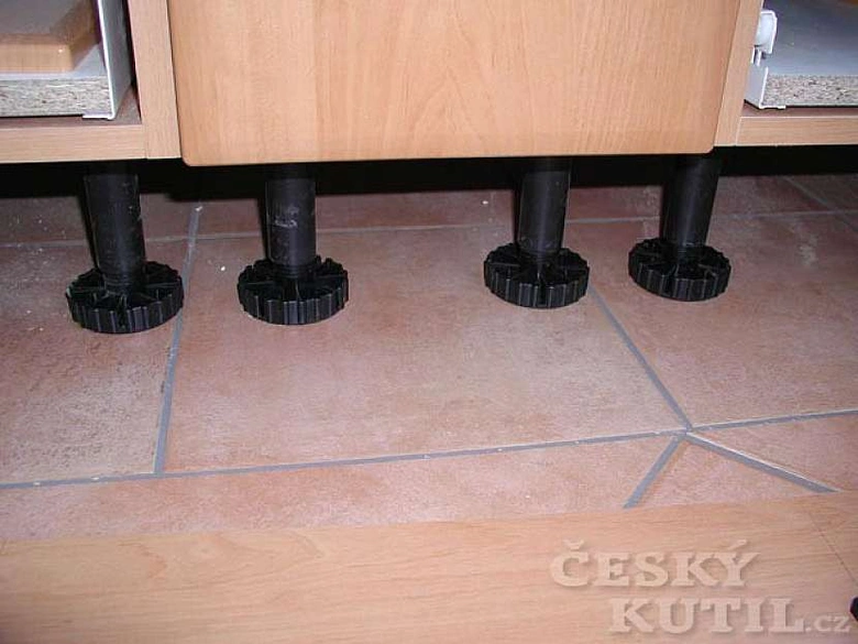 Černé nastavitelné patky pod dřevěnou skříň na dlažbě