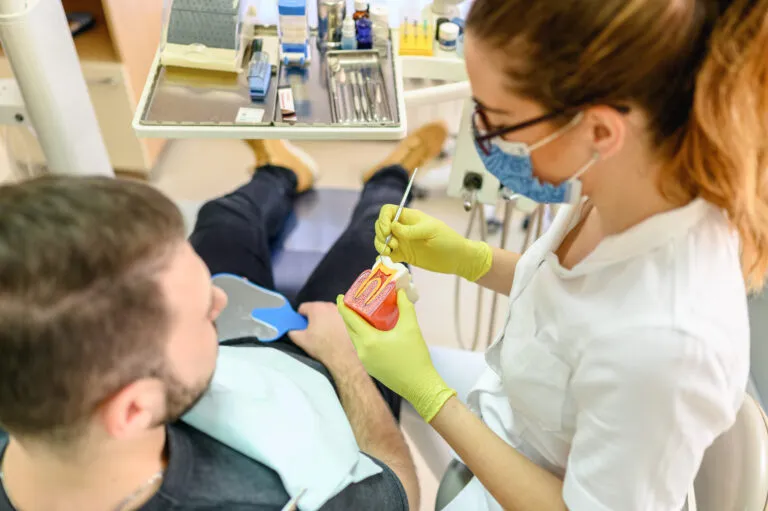 Zubní lékařka vyšetřuje pacientovy dásně v ordinaci.